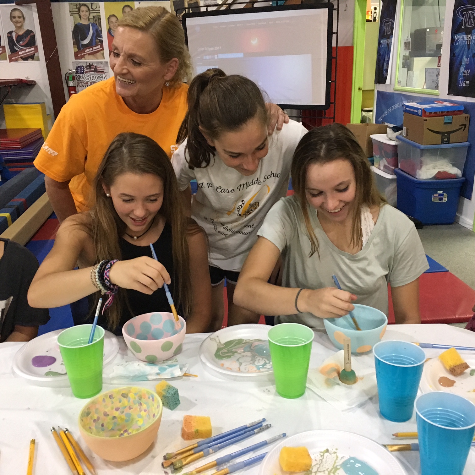 Coach Chris and team girls paint bowls for the Annual Empty Bowl charity event